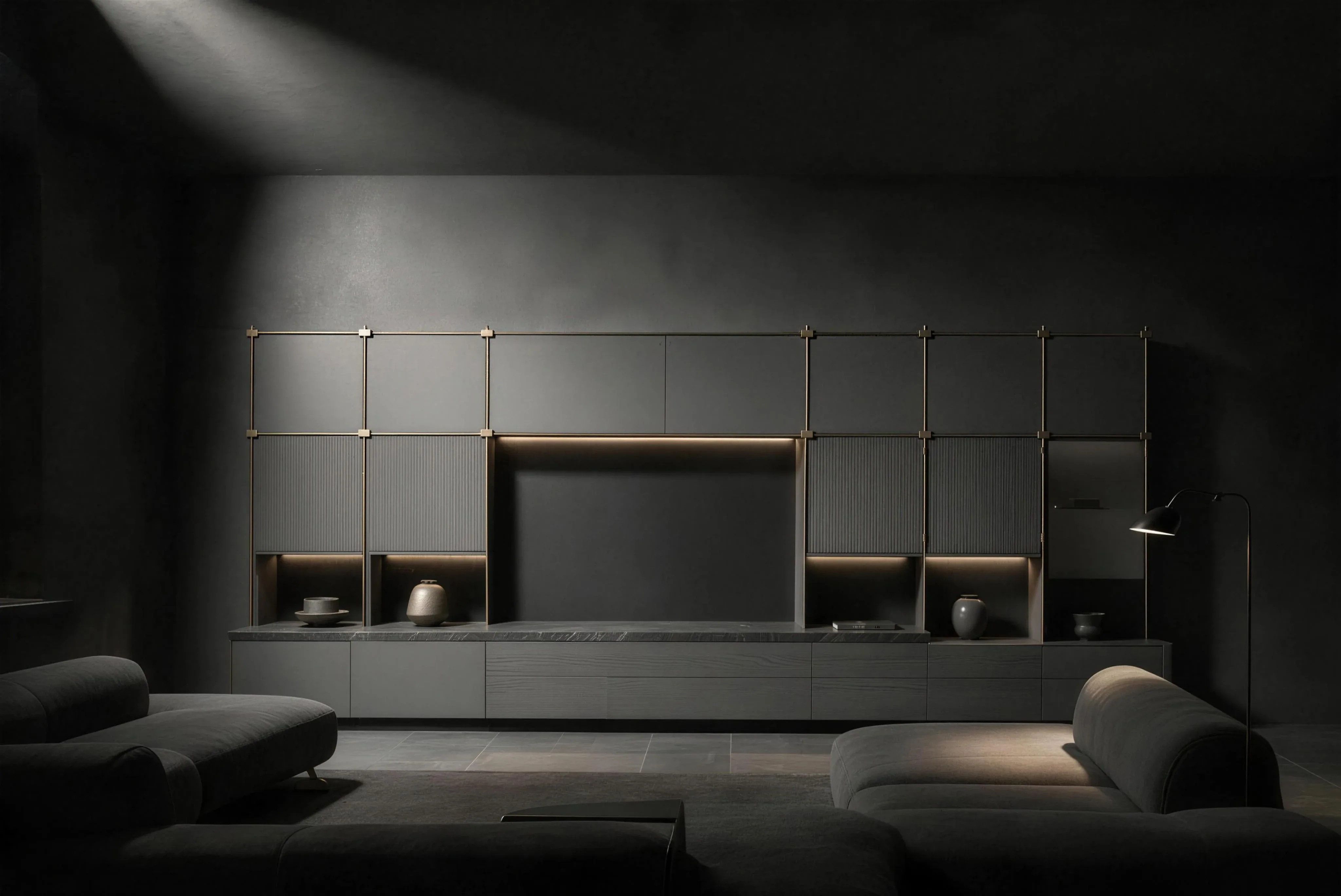 A fitted media wall across a dark living room, a screen set into the grid, lit niches and a low grey sofa